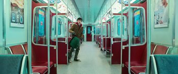 Movie still from “Shazam!” (2019), directed by David F. Sandberg – A person standing on a train holding a green bag; Wide shot, High angle