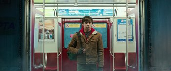 Movie still from “Shazam!” (2019), directed by David F. Sandberg – A man standing on a train holding a bag; Medium shot, Low angle