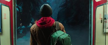Movie still from “Shazam!” (2019), directed by David F. Sandberg – A man with a backpack and hat looking at a cave; Medium shot, Low angle