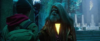 Movie still from “Shazam!” (2019), directed by David F. Sandberg – A man with a beard and long hair is holding a glowing stick; Medium shot, Over the shoulder angle