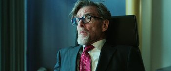 Movie still from “Shazam!” (2019), directed by David F. Sandberg – An older man wearing a suit and tie sitting in a chair; Close Up shot, Over the shoulder angle