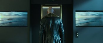 Movie still from “Shazam!” (2019), directed by David F. Sandberg – A man in a leather jacket standing next to an elevator; Medium shot, Low angle