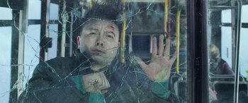 Movie still from “Shazam!” (2019), directed by David F. Sandberg – A man holding his hand up in a bus window; Medium shot, Overhead angle