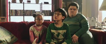 Movie still from “Shazam!” (2019), directed by David F. Sandberg – A group of people sitting on a couch watching television; Medium shot, Low angle