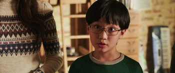 Movie still from “Shazam!” (2019), directed by David F. Sandberg – A young boy wearing glasses and a green shirt; Close Up shot, Over the shoulder angle