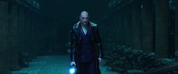 Movie still from “Shazam!” (2019), directed by David F. Sandberg – A bald man in a leather jacket holding a flashlight in the dark; Medium shot, Low angle