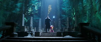 Movie still from “Shazam!” (2019), directed by David F. Sandberg – A man standing on some steps with a wand; Wide shot, Low angle