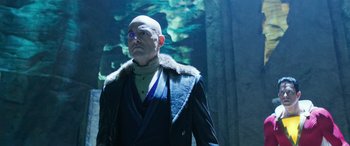 Movie still from “Shazam!” (2019), directed by David F. Sandberg – A bald man in a black jacket and blue glasses; Medium shot, Over the shoulder angle