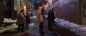 Movie still from “Shazam!” (2019), directed by David F. Sandberg – A man in a costume walking down a street; Wide shot, Over the shoulder angle