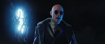 Movie still from “Shazam!” (2019), directed by David F. Sandberg – A bald man wearing sunglasses and a leather jacket; Medium shot, Low angle