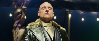 Movie still from “Shazam!” (2019), directed by David F. Sandberg – A bald man in a black leather jacket and a gold tie; Close Up shot, Low angle