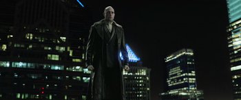 Movie still from “Shazam!” (2019), directed by David F. Sandberg – A bald man in a long coat stands in front of some buildings; Wide shot, Low angle