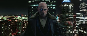Movie still from “Shazam!” (2019), directed by David F. Sandberg – A man with a bald head wearing a black coat; Close Up shot, Over the shoulder angle