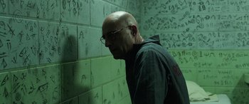 Movie still from “Shazam!” (2019), directed by David F. Sandberg – A bald man with glasses leaning up against a wall; Medium shot, Low angle