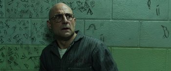 Movie still from “Shazam!” (2019), directed by David F. Sandberg – A bald man with glasses is standing in front of a wall; Close Up shot, Low angle