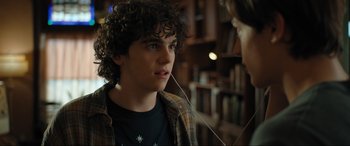 Movie still from “Shazam! Fury of the Gods” (2023), directed by David F. Sandberg – A young man with curly hair listening to music with headphones; Close Up shot, Over the shoulder angle