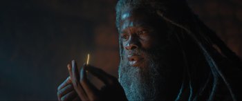 Movie still from “Shazam! Fury of the Gods” (2023), directed by David F. Sandberg – A man with a beard holding a lit cigarette; Close Up shot, Low angle