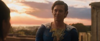 Movie still from “Shazam! Fury of the Gods” (2023), directed by David F. Sandberg – A man wearing a blue and yellow costume; Close Up shot, Over the shoulder angle