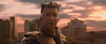 Movie still from “Shazam! Fury of the Gods” (2023), directed by David F. Sandberg – An older woman wearing a golden outfit and antler headband; Close Up shot, Over the shoulder angle