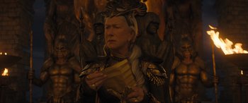 Movie still from “Shazam! Fury of the Gods” (2023), directed by David F. Sandberg – An older woman wearing a crown and holding a book; Close Up shot, Low angle