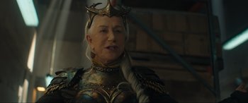 Movie still from “Shazam! Fury of the Gods” (2023), directed by David F. Sandberg – An older woman wearing a golden outfit and a crown; Close Up shot, Over the shoulder angle