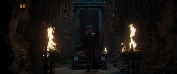 Movie still from “Shazam! Fury of the Gods” (2023), directed by David F. Sandberg – A man in a costume standing in front of a fire pit; Wide shot, High angle