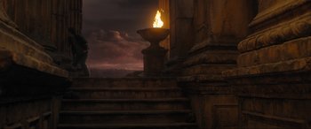 Movie still from “Shazam! Fury of the Gods” (2023), directed by David F. Sandberg – A lit candle in a stone urn near a pillar; Extreme Wide shot, High angle