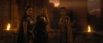 Movie still from “Shazam! Fury of the Gods” (2023), directed by David F. Sandberg – A group of people standing next to each other in costumes; Medium shot, Over the shoulder angle