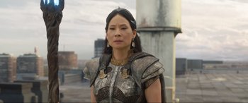 Movie still from “Shazam! Fury of the Gods” (2023), directed by David F. Sandberg – A woman wearing a metal armor and gold jewelry; Close Up shot, Over the shoulder angle
