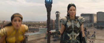 Movie still from “Shazam! Fury of the Gods” (2023), directed by David F. Sandberg – A woman standing next to a wooden staff; Medium shot, Over the shoulder angle