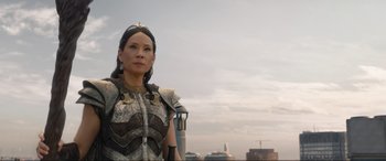 Movie still from “Shazam! Fury of the Gods” (2023), directed by David F. Sandberg – A woman in a costume standing in front of a sky background; Medium shot, Over the shoulder angle
