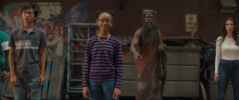 Movie still from “Shazam! Fury of the Gods” (2023), directed by David F. Sandberg – A girl standing in front of a statue of an old man; Medium shot, Low angle
