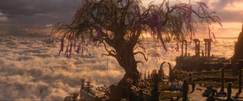Movie still from “Shazam! Fury of the Gods” (2023), directed by David F. Sandberg – A tree with purple flowers hanging from it's branches in front of a cloudy sky; Extreme Wide shot, High angle