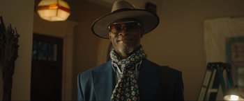 Movie still from “Shazam! Fury of the Gods” (2023), directed by David F. Sandberg – A man wearing a hat and sunglasses and a blue suit; Close Up shot, Low angle
