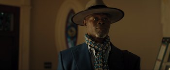 Movie still from “Shazam! Fury of the Gods” (2023), directed by David F. Sandberg – A man wearing a hat and a tie; Close Up shot, Low angle