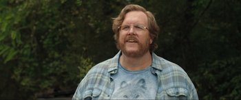 Movie still from “Shazam! Fury of the Gods” (2023), directed by David F. Sandberg – A person wearing glasses and a plaid shirt; Close Up shot, Over the shoulder angle