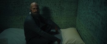 Movie still from “Shazam! Fury of the Gods” (2023), directed by David F. Sandberg – A man sitting on top of a bed next to a pillow; Medium shot, High angle