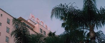 Movie still from “Shelter in Place” (2021), directed by Connor Martin – A building with a hotel sign on the top of it; Extreme Wide shot, Low angle