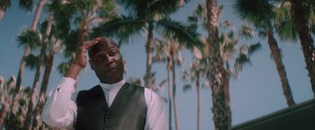 Movie still from “Shelter in Place” (2021), directed by Connor Martin – A man standing in front of some palm trees; Medium shot, Low angle