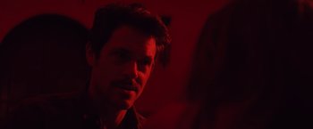 Movie still from “Shelter in Place” (2021), directed by Connor Martin – A person in a room with red lighting; Close Up shot, Over the shoulder angle