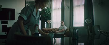 Movie still from “Shelter in Place” (2021), directed by Connor Martin – A man and a woman sitting on a couch; Wide shot, Over the shoulder angle