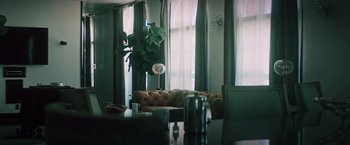 Movie still from “Shelter in Place” (2021), directed by Connor Martin – A living room filled with furniture next to a large window; Wide shot, Low angle