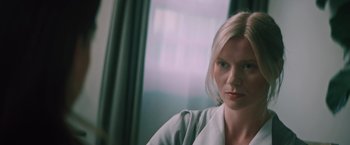 Movie still from “Shelter in Place” (2021), directed by Connor Martin – A woman sitting in front of a window looking at the camera; Close Up shot, Over the shoulder angle