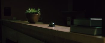 Movie still from “Shelter in Place” (2021), directed by Connor Martin – A bell on the counter next to a potted plant; Extreme Close Up shot, High angle