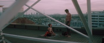 Movie still from “Shelter in Place” (2021), directed by Connor Martin – A man and a woman are sitting on the roof of a building; Wide shot, Low angle