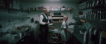 Movie still from “Shelter in Place” (2021), directed by Connor Martin – A man and a woman are standing in a kitchen; Medium shot, Low angle