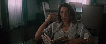 Movie still from “Shelter in Place” (2021), directed by Connor Martin – A woman sitting in a chair reading a book; Close Up shot, Over the shoulder angle