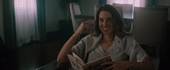 Movie still from “Shelter in Place” (2021), directed by Connor Martin – A woman sitting at a table holding a book; Close Up shot, Over the shoulder angle