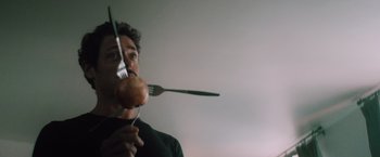 Movie still from “Shelter in Place” (2021), directed by Connor Martin – A man holding a fork and apple in front of his face; Close Up shot, Low angle