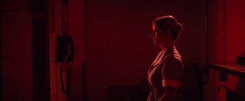 Movie still from “Shelter in Place” (2021), directed by Connor Martin – A woman standing in front of a red wall; Medium shot, Low angle